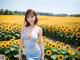 A woman in a blue dress standing in a field of sunflowers.