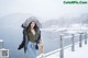 A woman standing on a wooden pier in the snow.