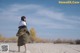 A woman standing in the middle of a sandy field.