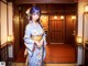 A woman in a blue kimono standing in a room.