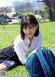 A young woman sitting on the grass with a backpack.