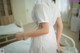 A woman in a white dress standing in a hospital room.