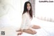 A woman sitting on top of a white bed.