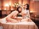 A couple of naked women sitting on top of a bed.