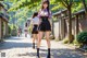 A woman in a purple shirt and black skirt walking down a street.