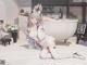 A girl in bunny ears sitting on a bed next to a bathtub.