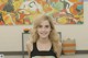 A woman standing in front of a painting in a room.